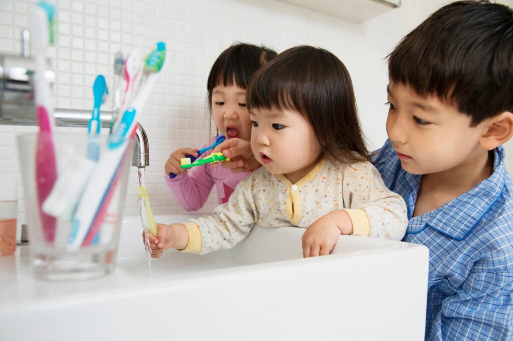 Brother helping sisters to clean teeth