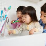 Brother helping sisters to clean teeth