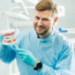 A model of a human jaw with teeth and a toothbrush in the dentist's hand