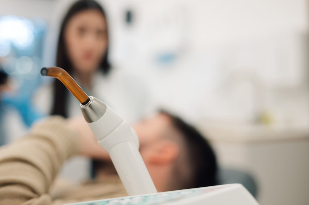 Dentist using uv light lamp during teeth whitening procedure