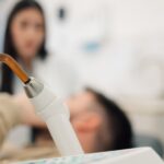 Dentist using uv light lamp during teeth whitening procedure