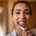Close-up of young woman cleaning teeth with a toothbrush