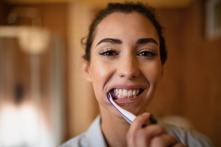 Close-up of young woman cleaning teeth with a toothbrush
